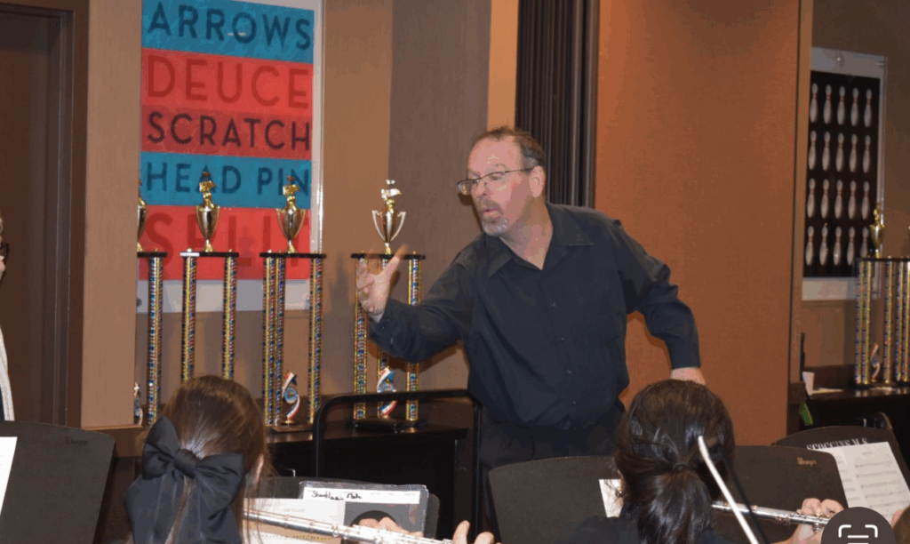 Man enthusiastically playing darts at an indoor event.