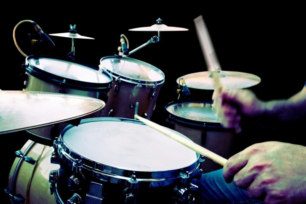 Close-up of a drummer playing a drum set with drumsticks.