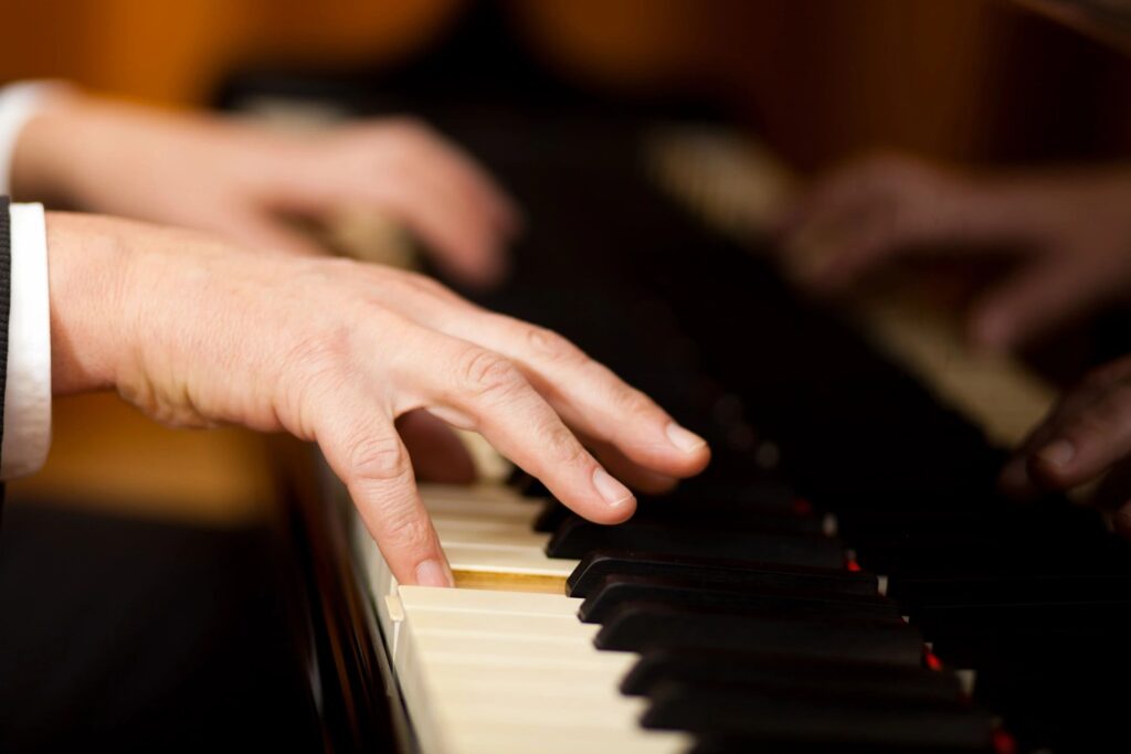 Close-up of hands playing piano keys.