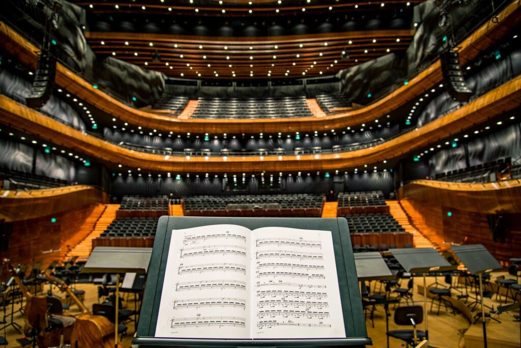 View from the conductor's podium overlooking a grand concert hall with sheet music in focus.
