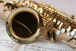 Saxophone resting on sheet music pages.