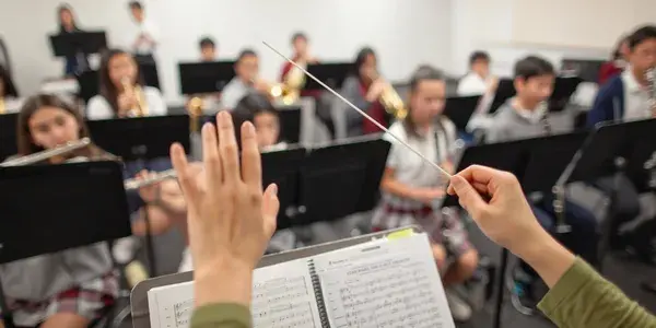 Conductor leading school band rehearsal session.